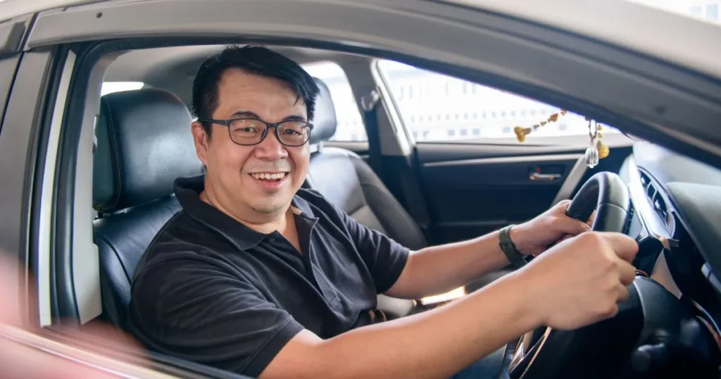 Man in a car smiling out of his window.