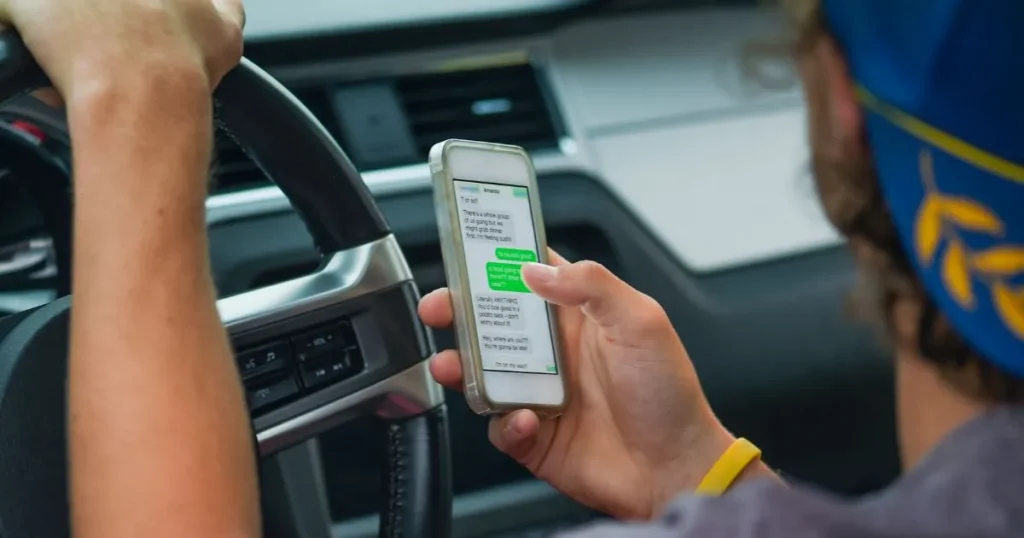 Individual distracted on his phone while driving a car.