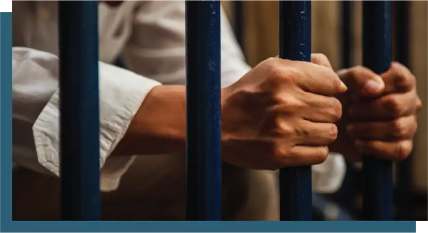 Person holding jail bars, symbolizing incarceration or justice.
