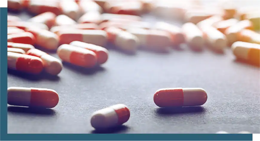 Assorted pills and capsules scattered on a surface for medication management.