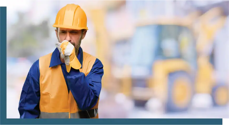 Construction worker wearing safety helmet and gloves at a building site.