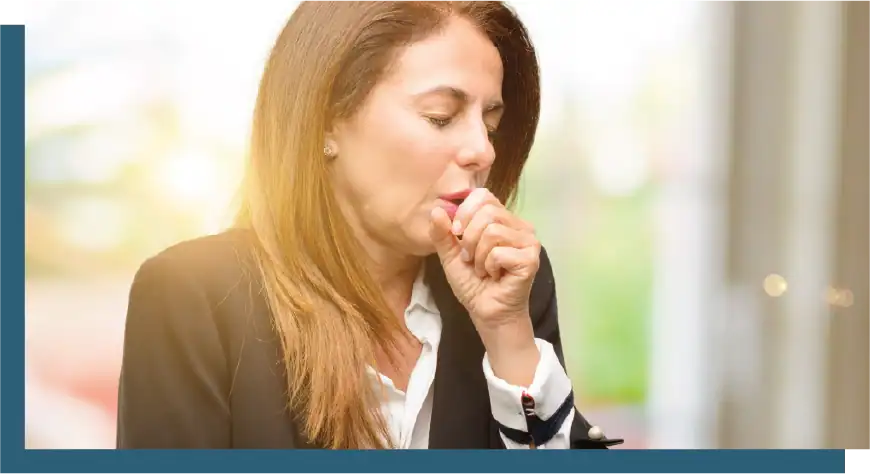 Businesswoman coughing into her hand in an office setting.