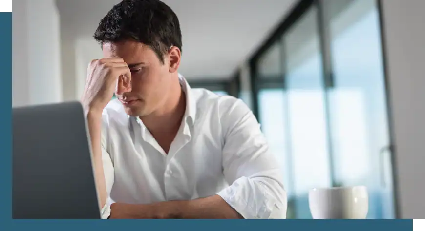 Frustrated man working on laptop in modern office setting.