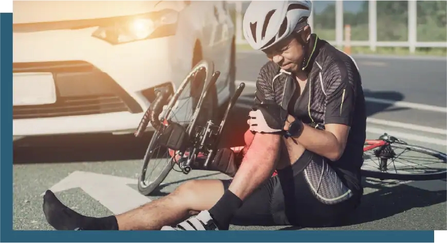 Cyclist with leg injury after fall on the road, receiving medical care.