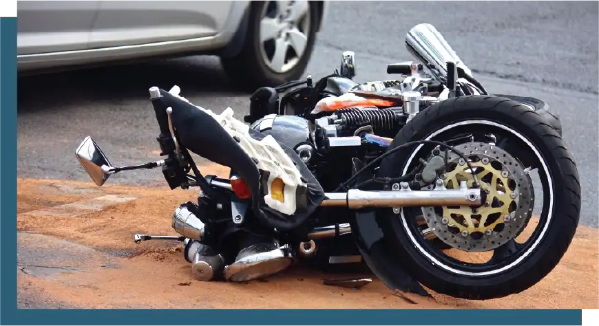 Motorcycle crash aftermath showing a fallen bike with visible damage on the street.