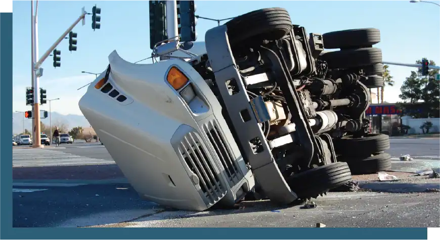 Accident scene showing overturned truck on city street with debris and traffic signals.