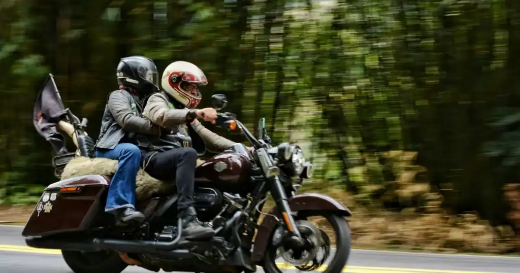 Two motorcyclists riding on a forested road with motion blur background.