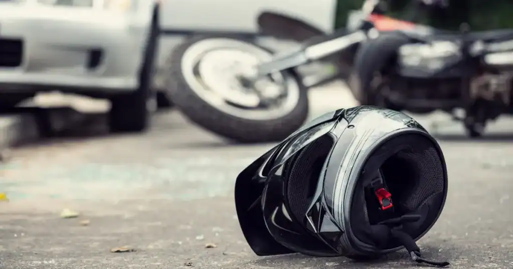 Black motorcycle helmet on the ground with a motorcycle in the background.